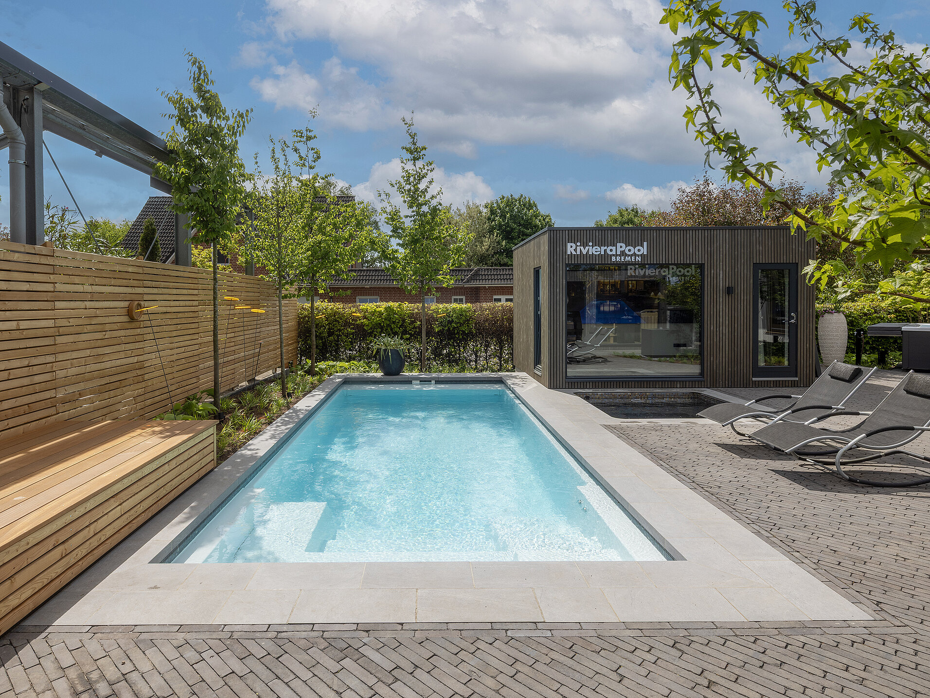 Langer Modena Pool mit Holzterrasse und Glasfassade – Premium-Beispiel der RivieraPool Ausstellung Bremen