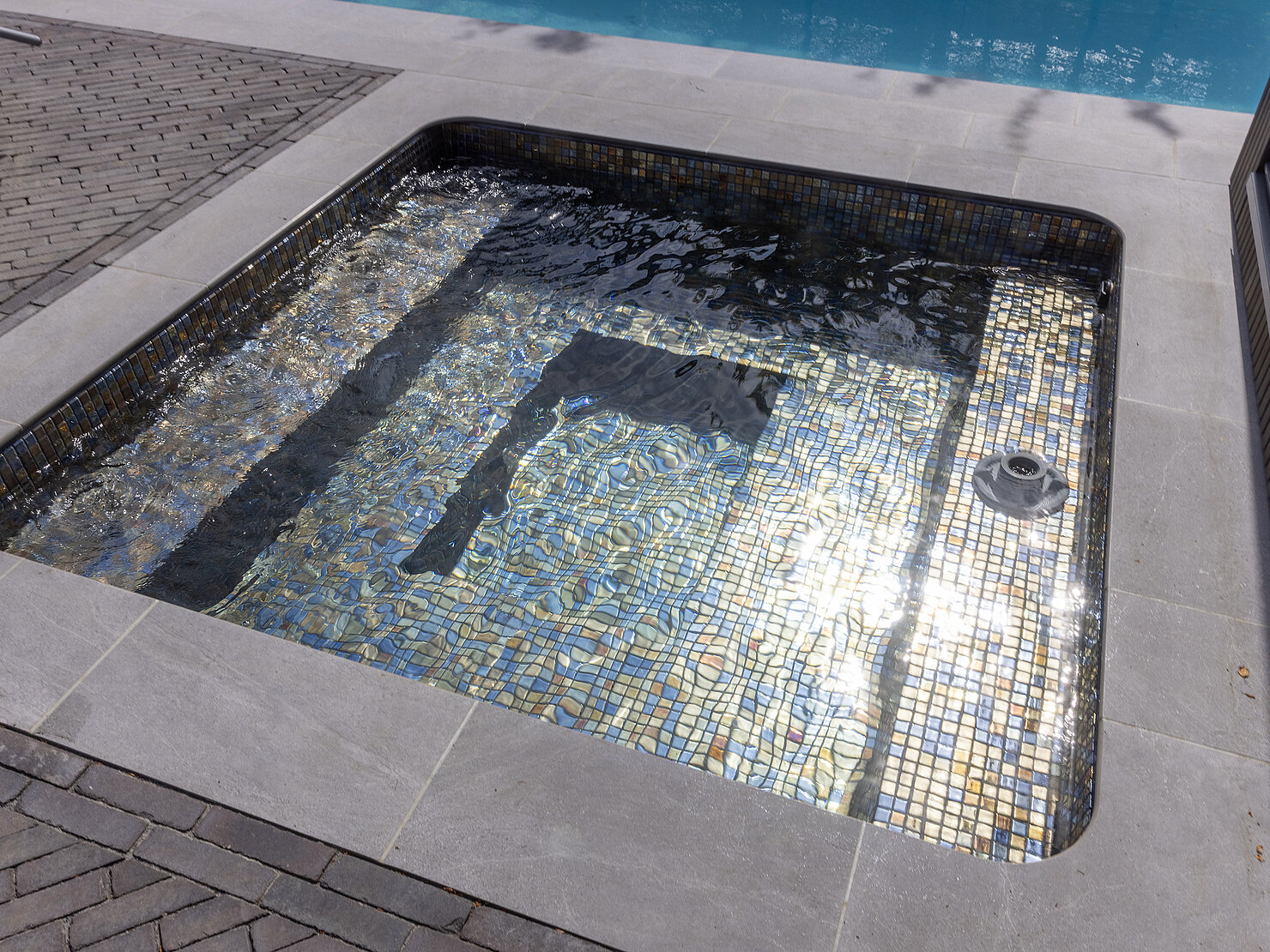Schimmerndes Wasser über Sitzbank des CSIDE 21 – Detail Glasmosaik & Whirlpool-Düsen